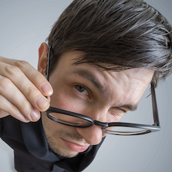 Young skeptic man with glasses is looking at you. View from above.